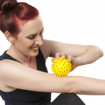 Frau massiert mit einem Noppenball ihren Arm beim Faszientraining.
